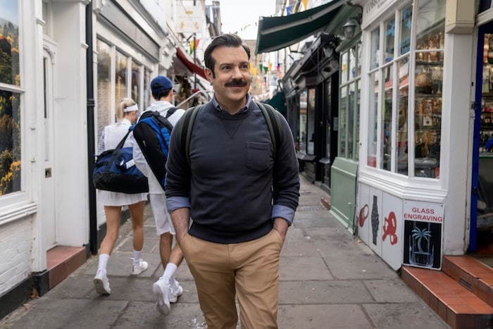 Jason Sudeikis walks down the street in Ted Lasso.