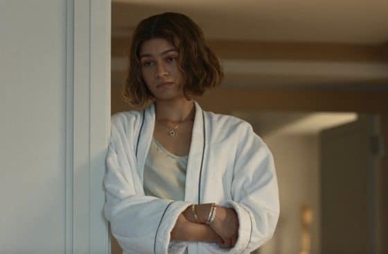 Zendaya stands with her hands crossed against a wall.