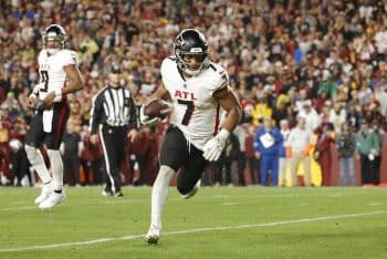Bijan Robinson holds the ball and runs.