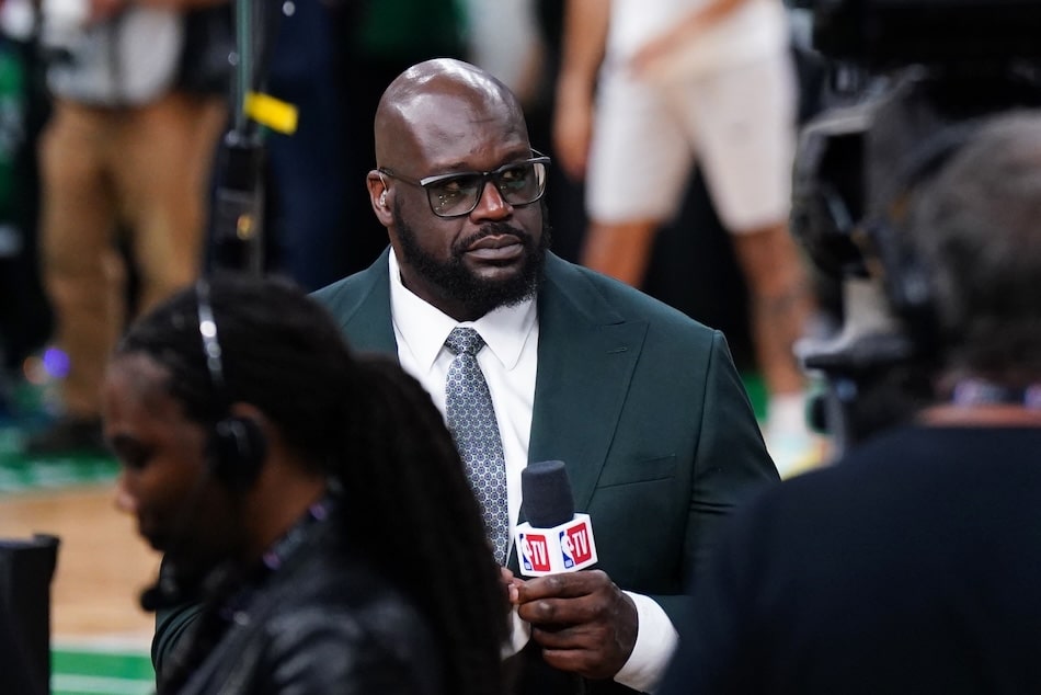 Shaquille O'Neal holds a mic.