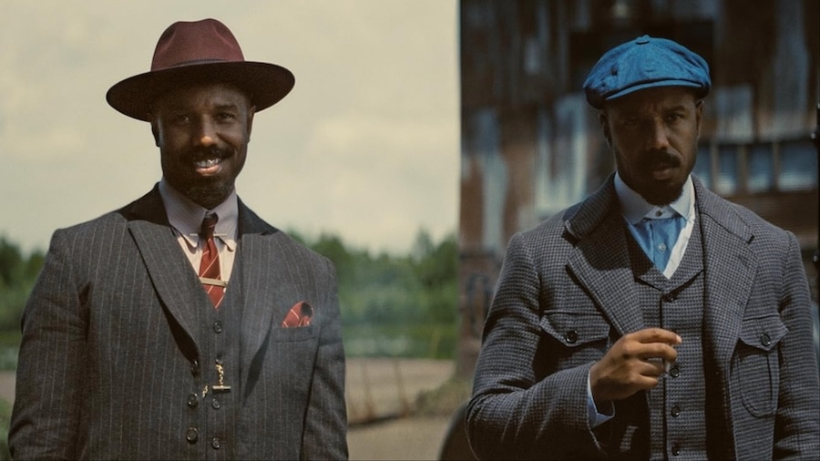 Two men smirk and stand next to each other.