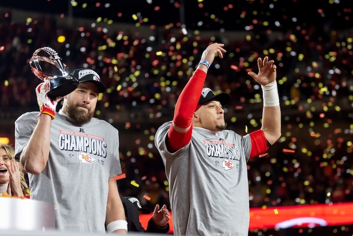 Confetti falls as Kansas City Chiefs tight end Travis Kelce (left) celebrates with the Lamar Hunt Trophy with quarterback Patrick Mahomes on the stage.