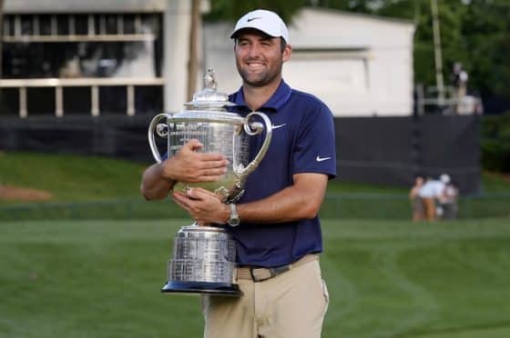 Scottie Scheffler hugs a trophy in his arms.