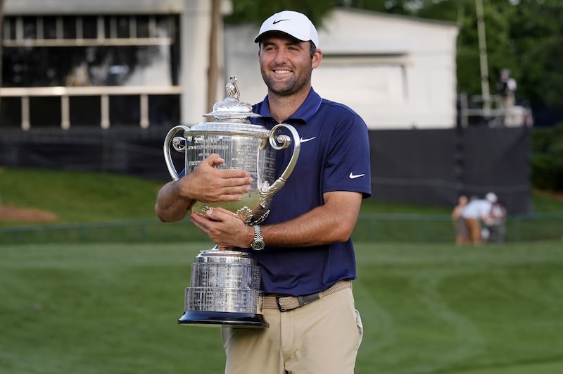 Scottie Scheffler hugs a trophy in his arms.