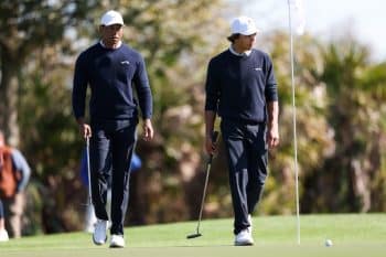 Tiger Woods and son Charlie Woods walk on the green.