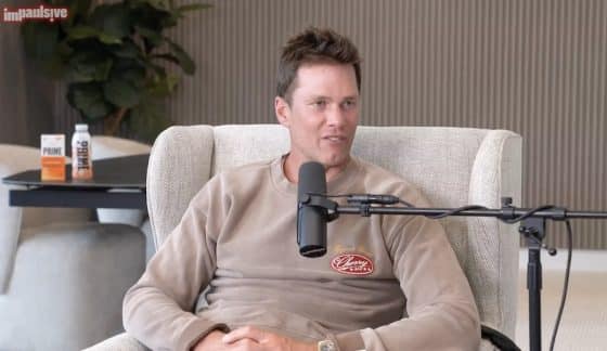 Tom Brady sits on a chair and behind a mic on the Impaulsive podcast.