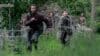 A man and boy run in a field.