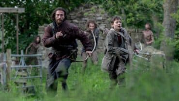 A man and boy run in a field.