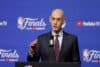 Adam Silver puts his hand up at the podium.