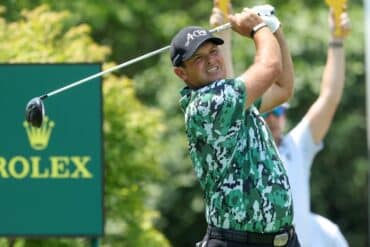Patrick Reed holds his club and poses.