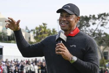 Tiger Woods holds a mic to his face.
