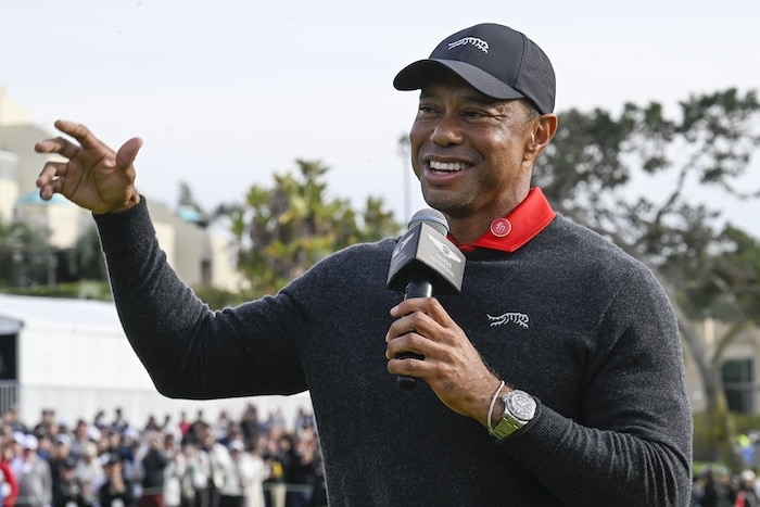 Tiger Woods holds a mic to his face.