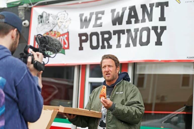 Dave Portnoy holds up a slice of pizza.