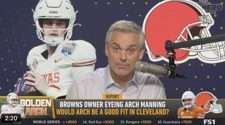 Colin Cowherd sits in front of a mic.