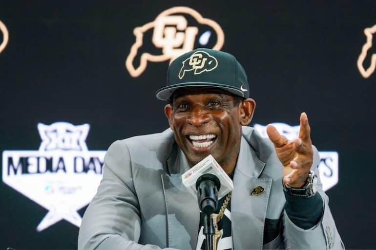 Deion Sanders sits at the podium.