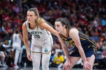 Two WNBA players stand on the court.