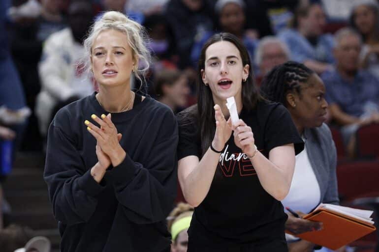 Sophe Cunningham and Caitlin Clark stand on the sidelines.