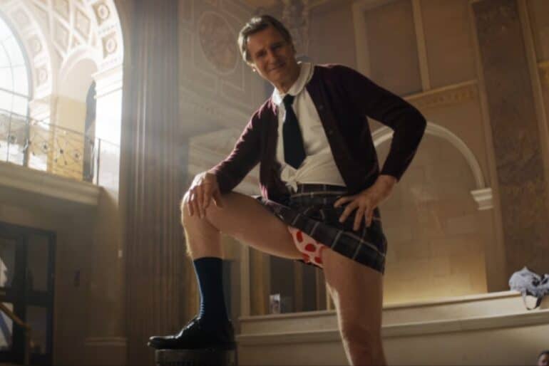 Liam Neeson puts his leg up.