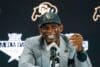 Deion Sanders sits at the mic.