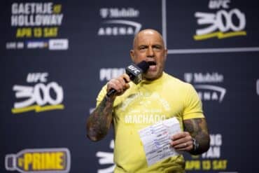 UFC announcer Joe Rogan holds a mic up to his face.