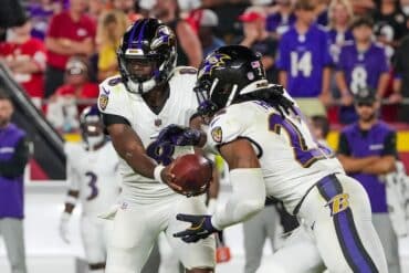 Lamar Jackson hands the ball off to Derrick Henry.