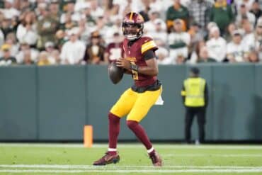 Jayden Daniels holds the ball and throws.