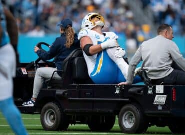 Joe Alt holds his knee on a cart.