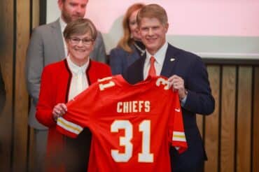 Clark Hunt holds a jersey up.