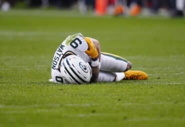 Christian Watson lays on the ground.