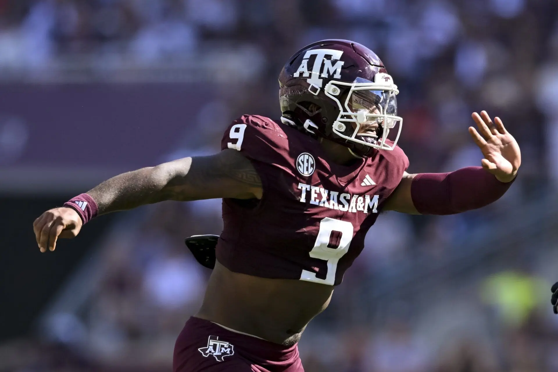 Cashius Howell in a maroon Texas A&M uniform, actively playing during a football game.