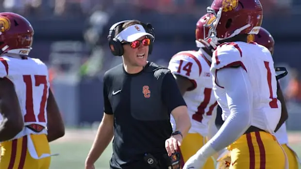 USC coach animatedly instructing players during a football game on the sidelines.