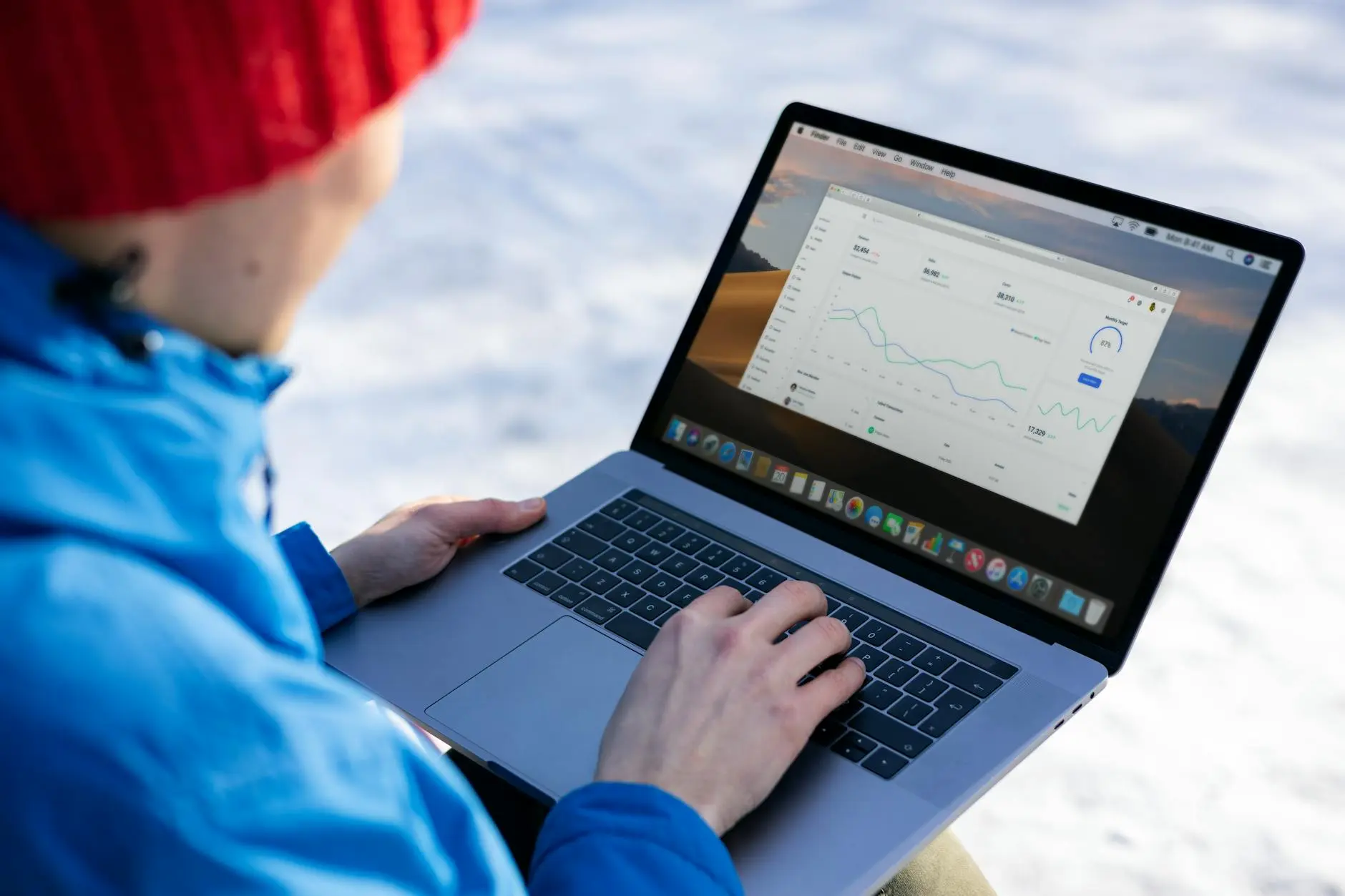 Person analyzing sports data on a laptop outdoors, showing data graphs.