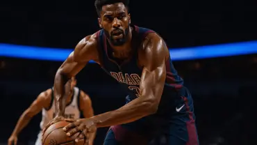 NBA power forward driving to basket in intense game action with dramatic arena lighting