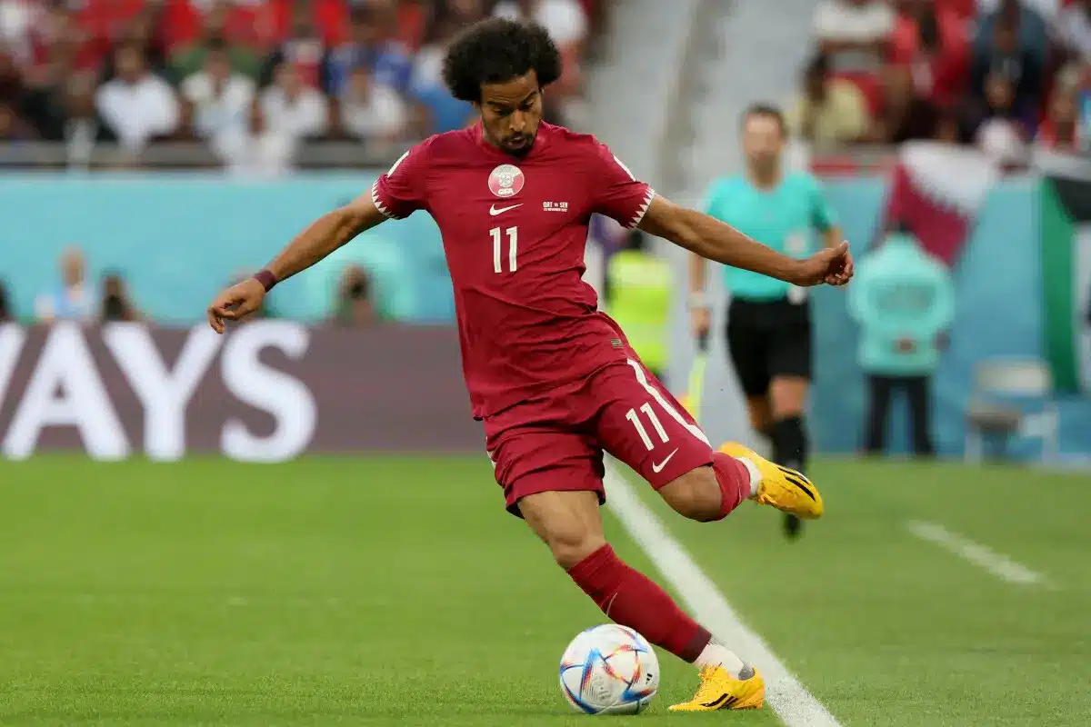 Akram Afif of Qatar executing a kick during a soccer match.