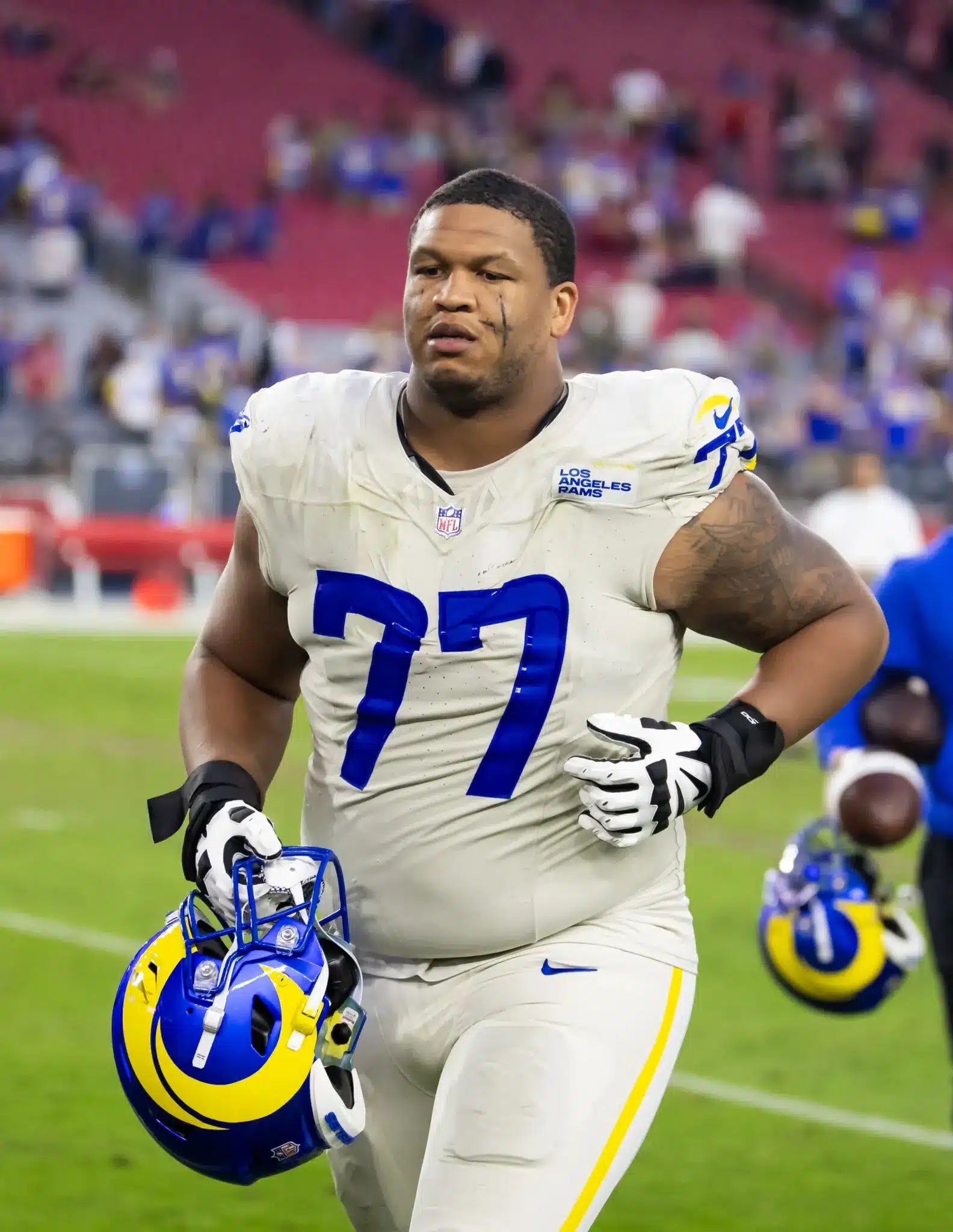 Alaric Jackson of the LA Rams walking off the field, holding his helmet.