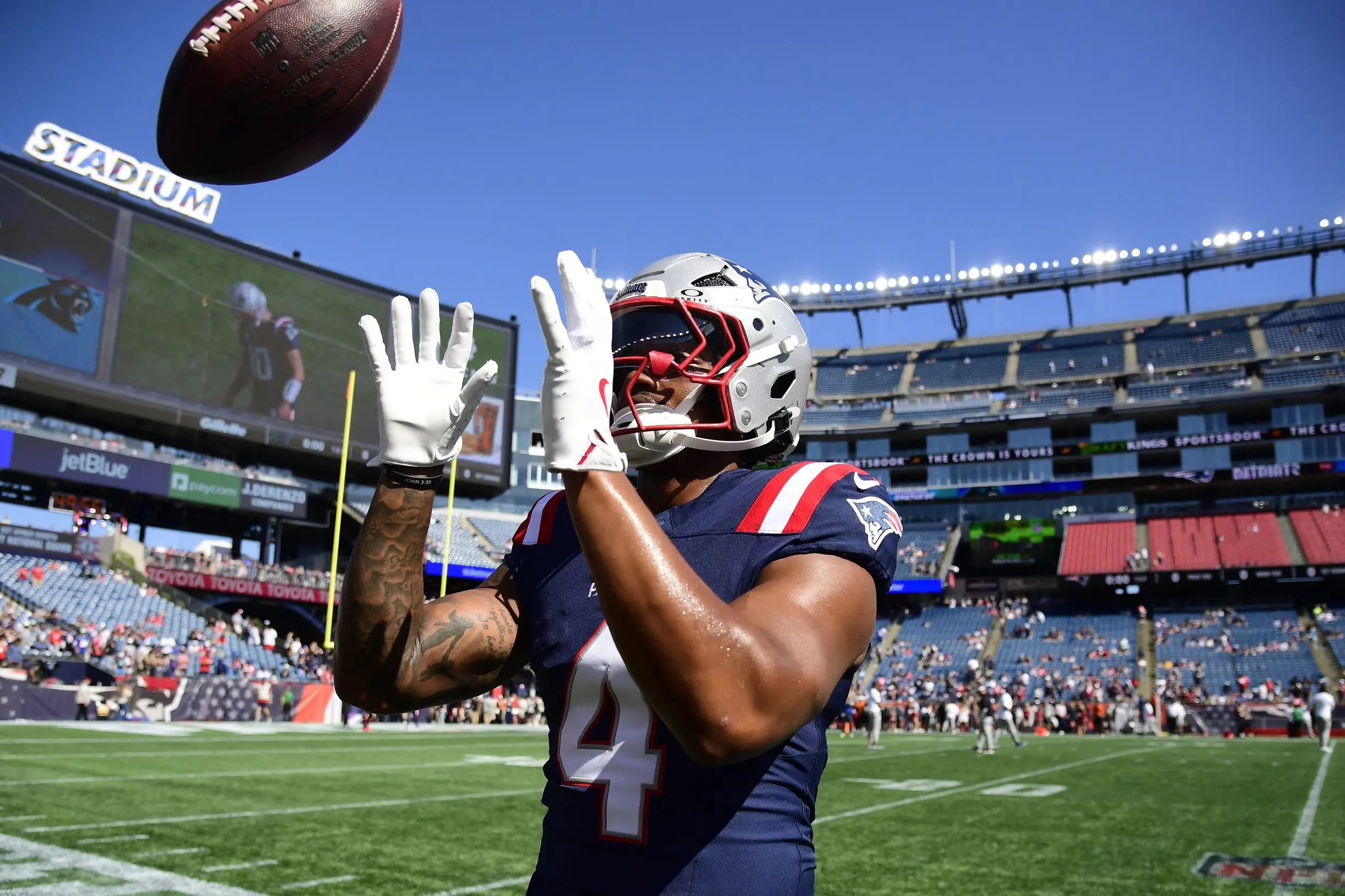 New England Patriots running back warms up on the field in uniform.