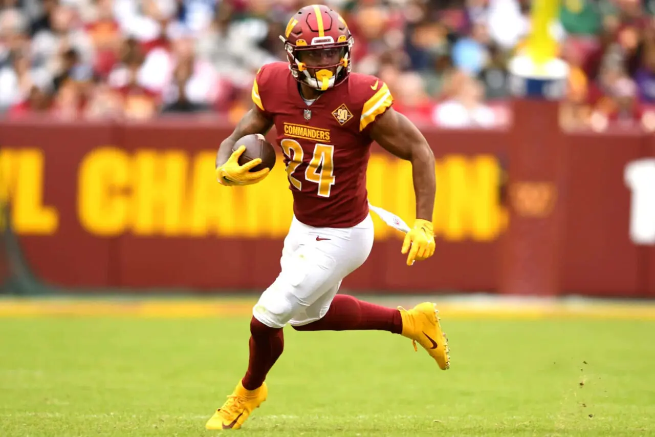 Antonio Gibson running with the football in a Washington Commanders uniform.