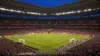 Packed World Cup stadium under floodlights during evening match with vibrant crowd and illuminated pitch