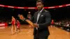 Basketball coach on sideline gesturing with clipboard during NBA game in professional arena
