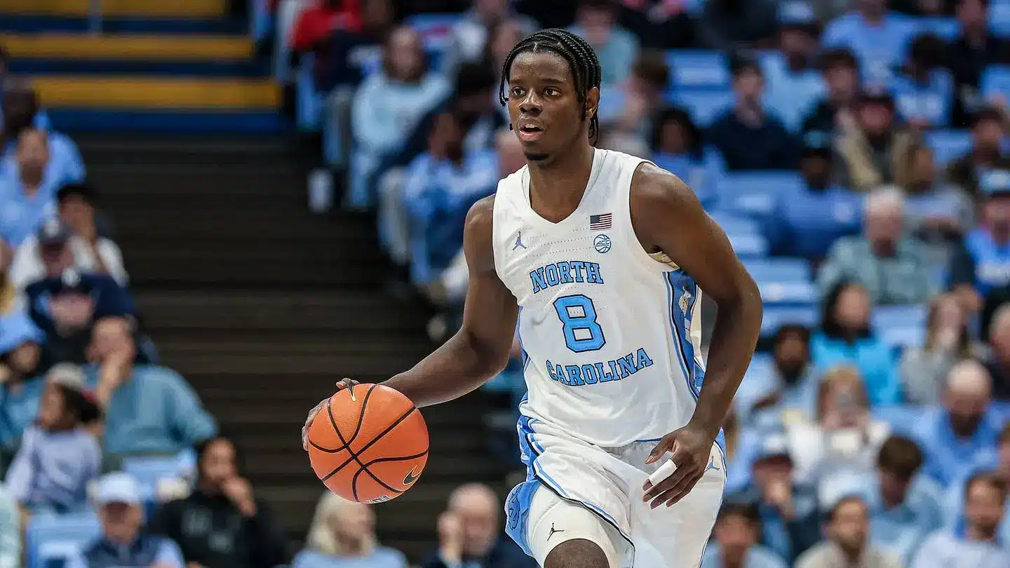 A basketball player in a North Carolina jersey dribbling a ball during a game.
