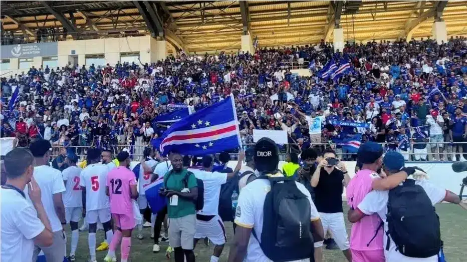 Cape Verde football team celebrating with fans, waving flags in a crowded stadium.