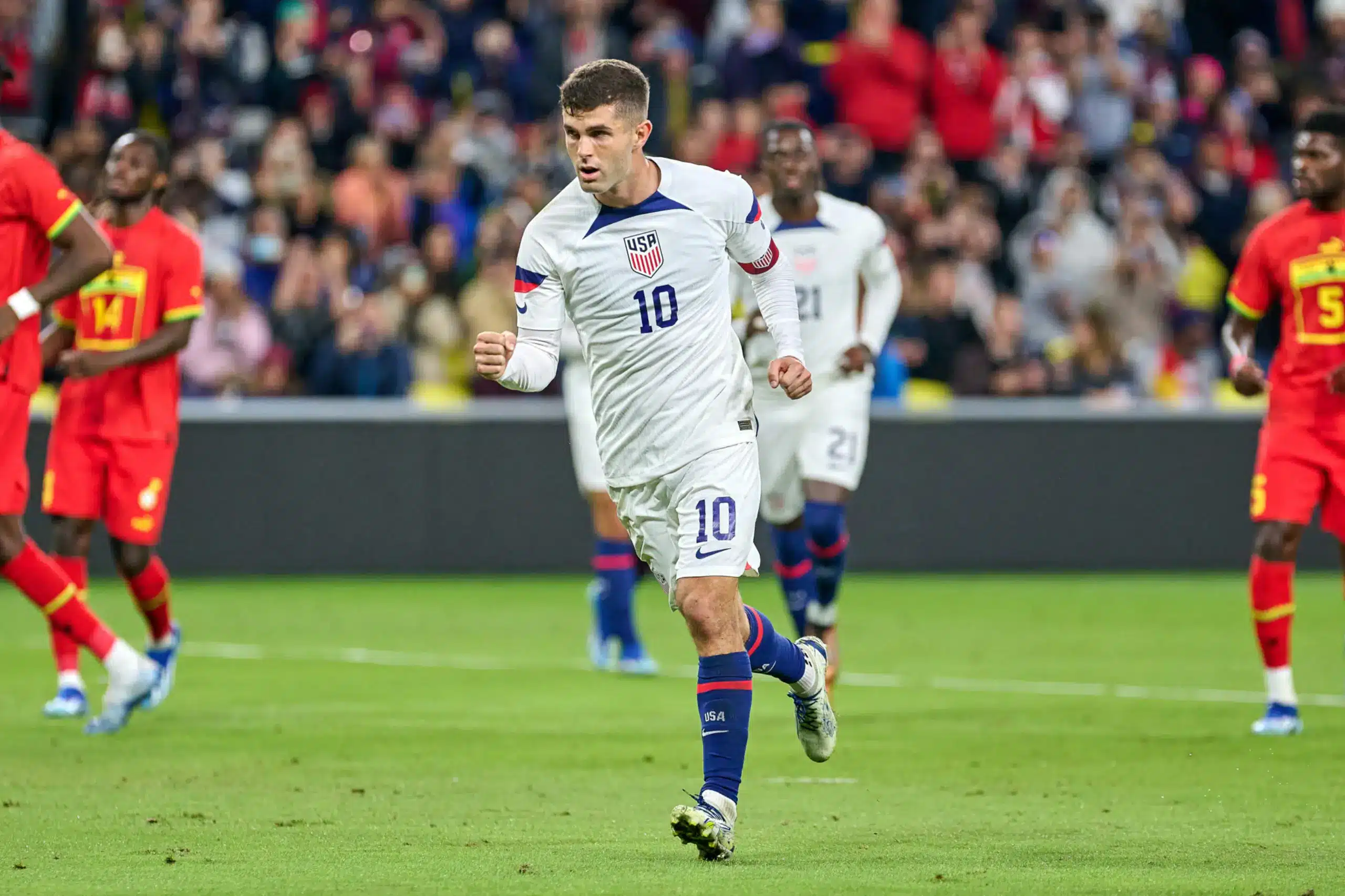 Christian Pulisic celebrating a goal in a USA soccer game against an opposing team.