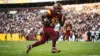 NFL running back in Washington Commanders uniform carrying football during game action