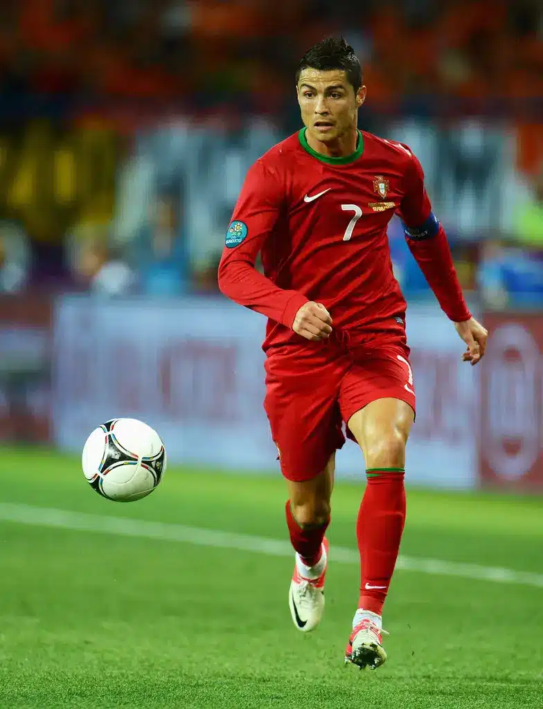 Cristiano Ronaldo in a Portugal national team uniform dribbling a soccer ball.