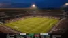 Aerial view of illuminated soccer stadium at dusk with pristine green pitch and packed stands