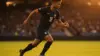 French soccer player in navy jersey sprinting with ball during World Cup match at stadium