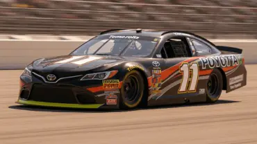 NASCAR Cup Series race car speeding through turn at Pocono Raceway in dramatic action shot