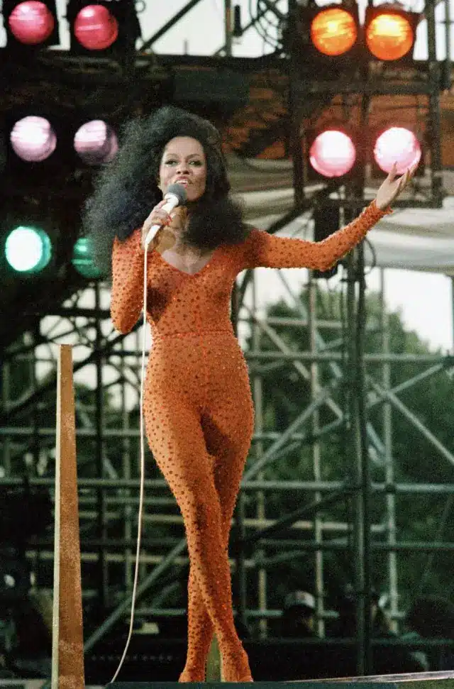 Diana Ross performing on stage in a sparkling orange outfit, 1980s.