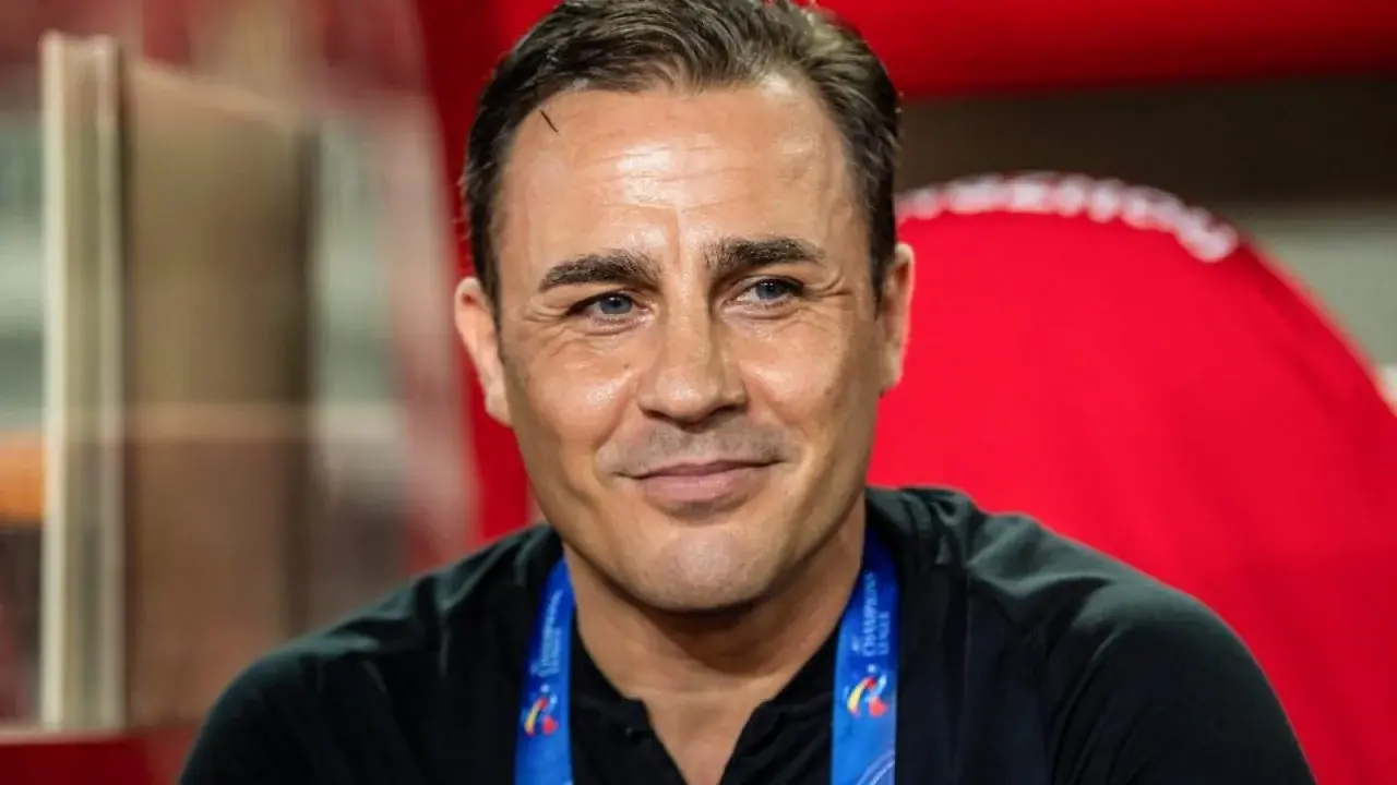 Close-up portrait of a smiling man with dark hair and a sports lanyard.