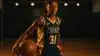 Young female basketball player holding ball in modern arena with dramatic lighting